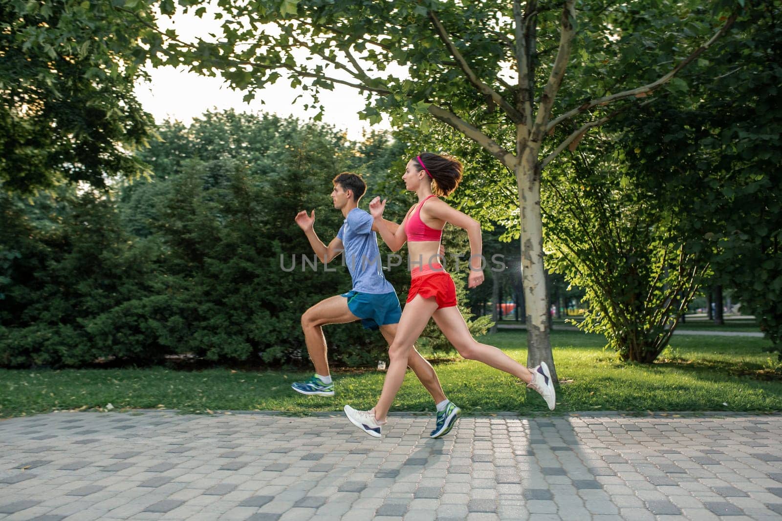 Portrait of cheerful caucasian couple running outdoors. Sport family