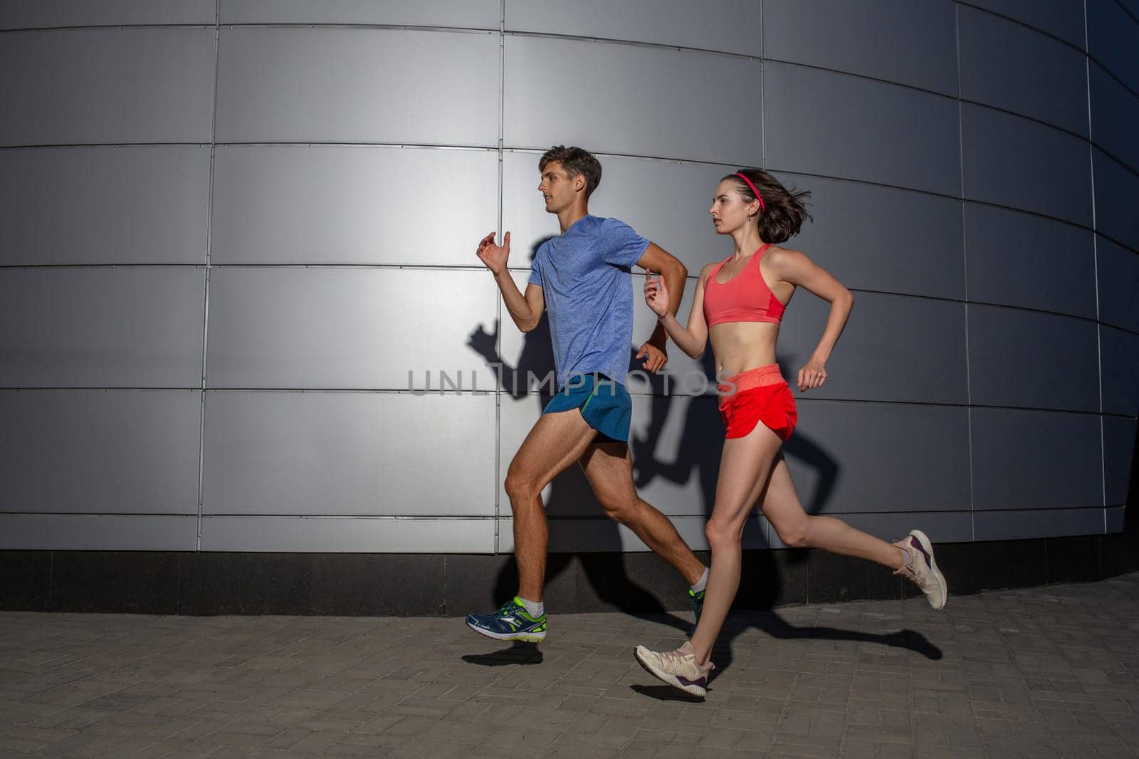 Active young couple jogging side by side in an urban street during their daily workout in a health and fitness concept by nazarovsergey