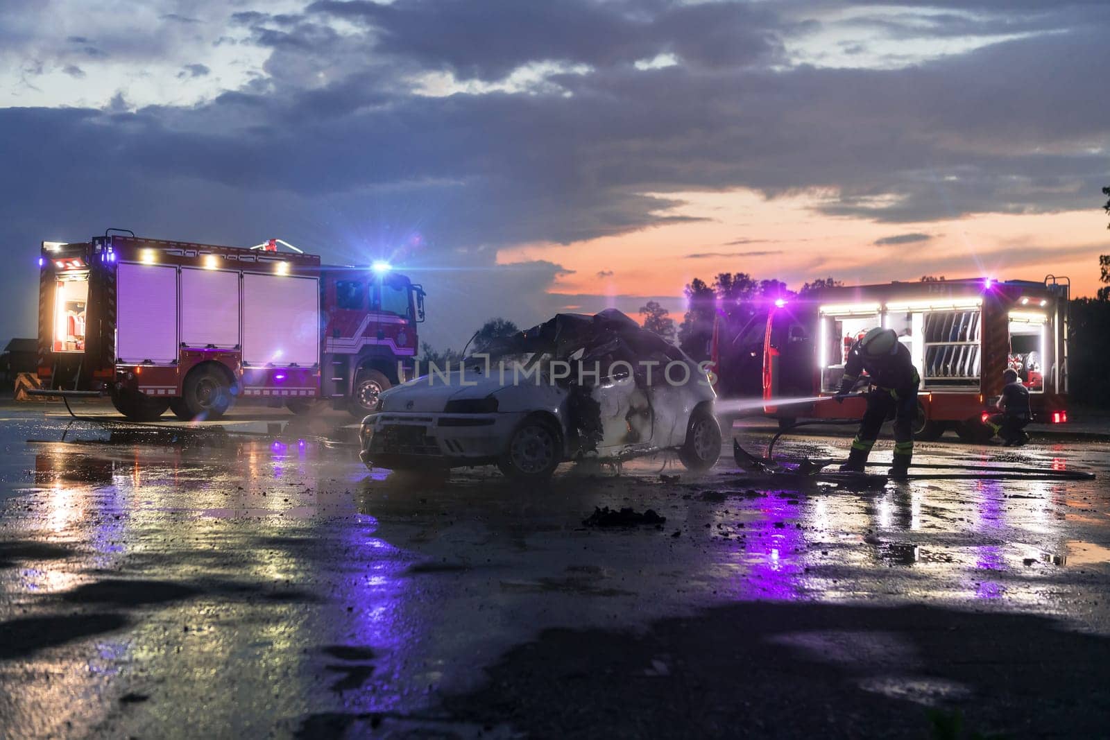 Firefighters using water fire extinguisher to fighting with the fire flame in car accident. Firefighter industrial and public safety concept rescue in night. by dotshock