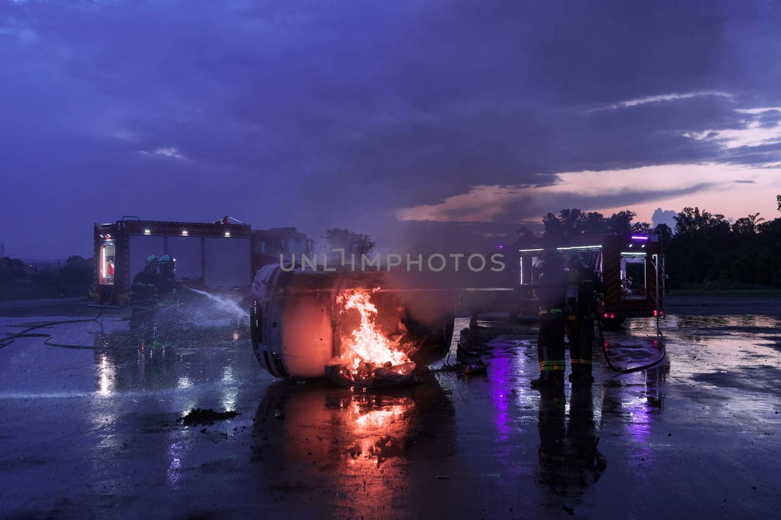 Firefighters using water fire extinguisher to fighting with the fire flame in car accident. Firefighter industrial and public safety concept rescue in night. High quality photo
