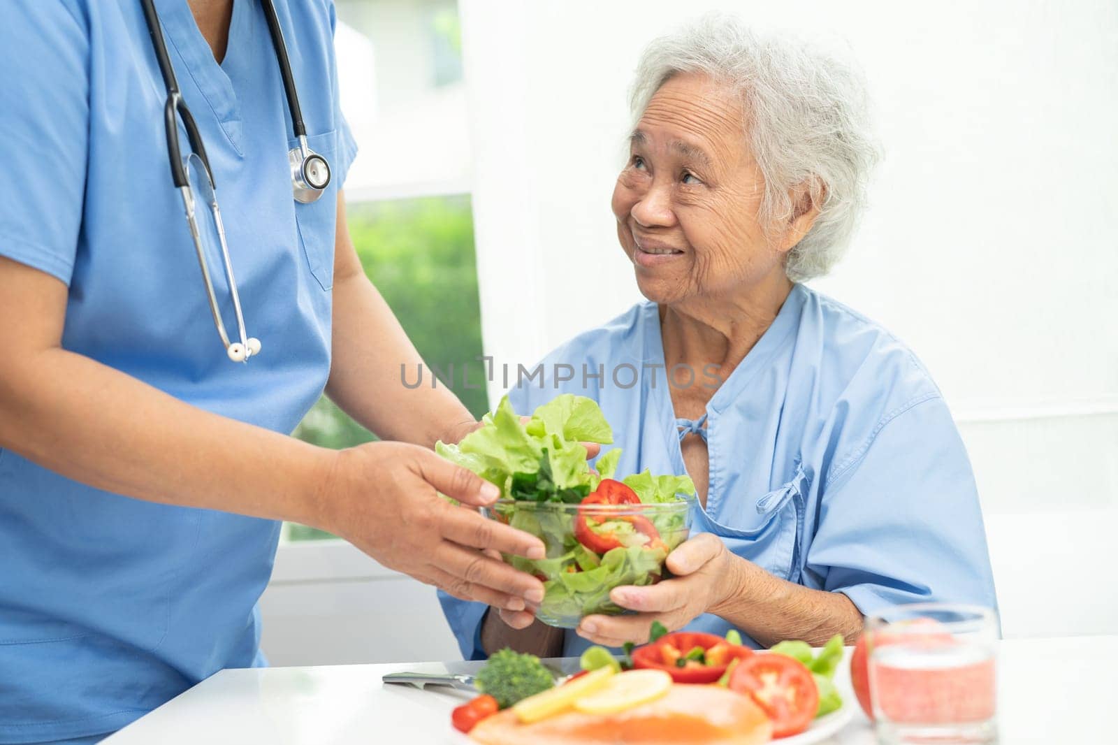 Asian elderly woman patient eating salmon steak breakfast with vegetable healthy food in hospital. by pamai