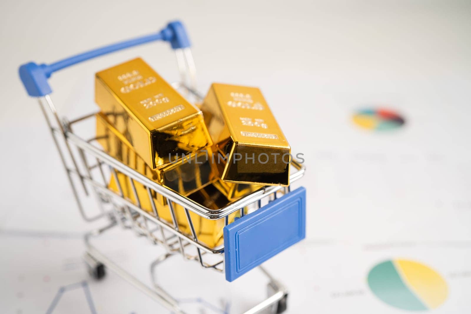 Gold bar in shopping cart on US dollar banknotes money and graph, economy finance exchange trade investment concept.