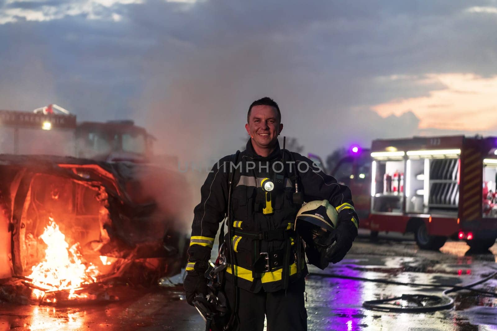 Portrait of a heroic fireman in a protective suit. Firefighter in fire fighting or car accident rescue operation in dusk or night. by dotshock