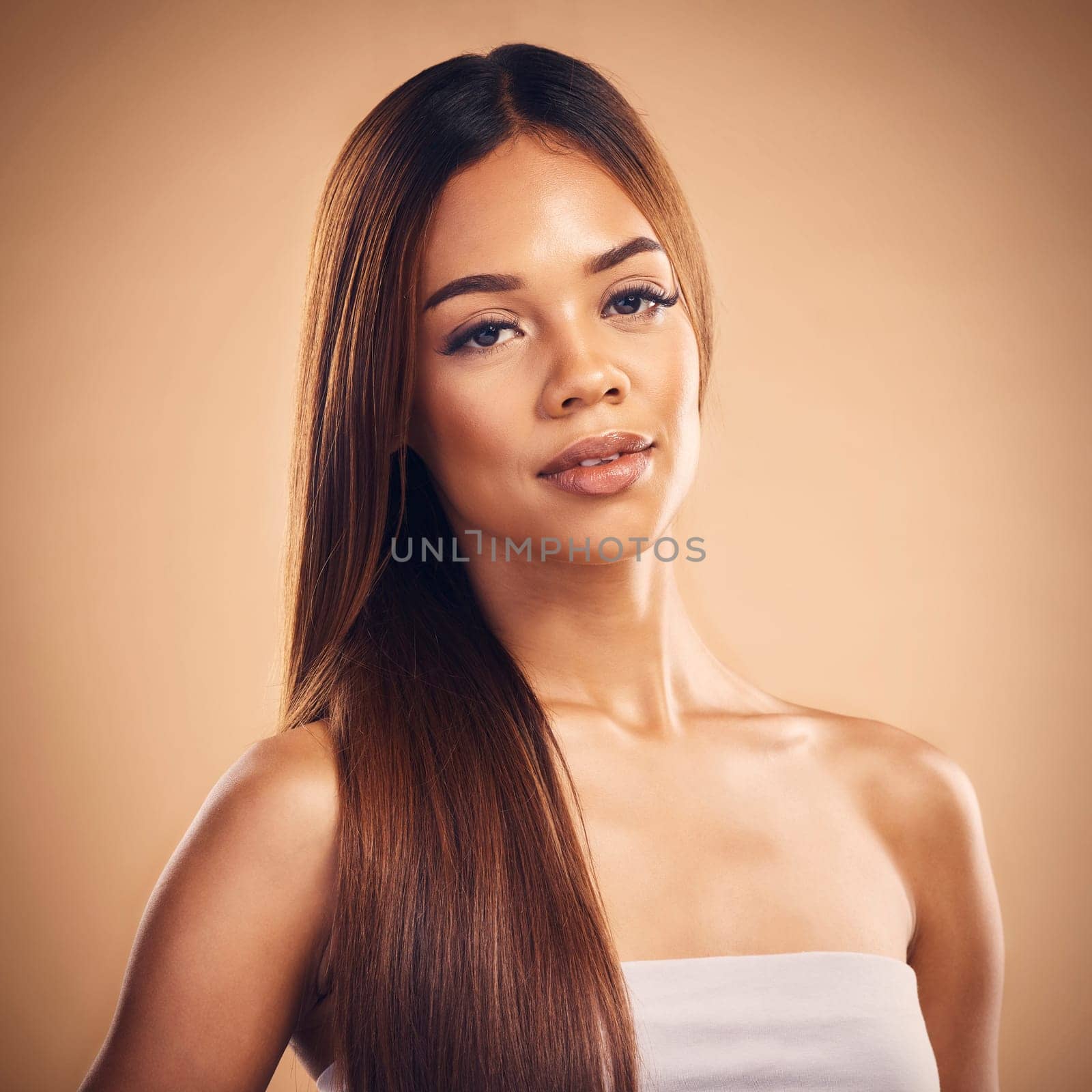 Woman, hair style and beauty in studio portrait with cosmetic wellness, glow and shine by brown background. Girl, latino model and haircare with makeup, health and cosmetics with growth by backdrop.