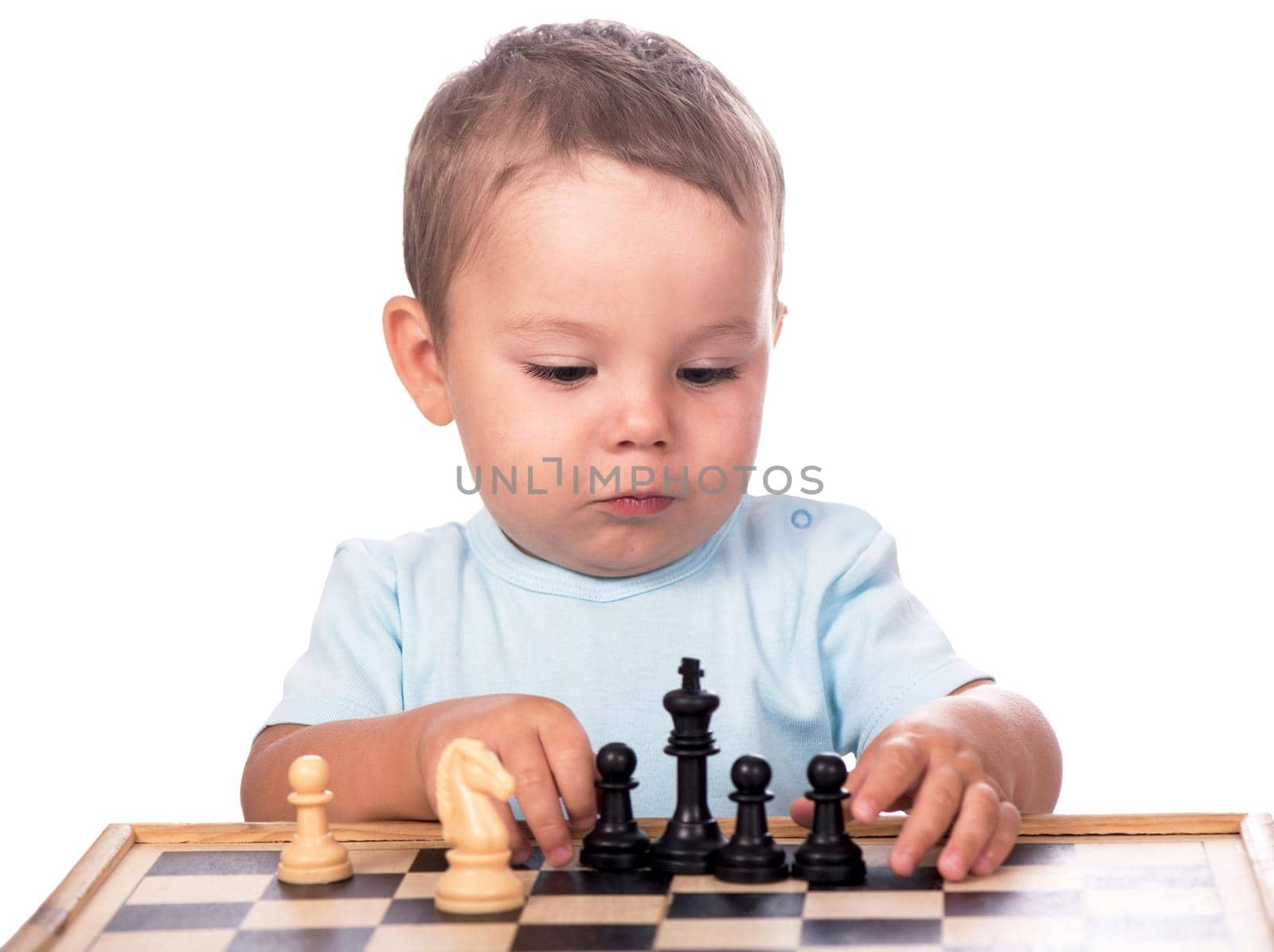 little boy staring at the chess pieces isolated on white background by aprilphoto