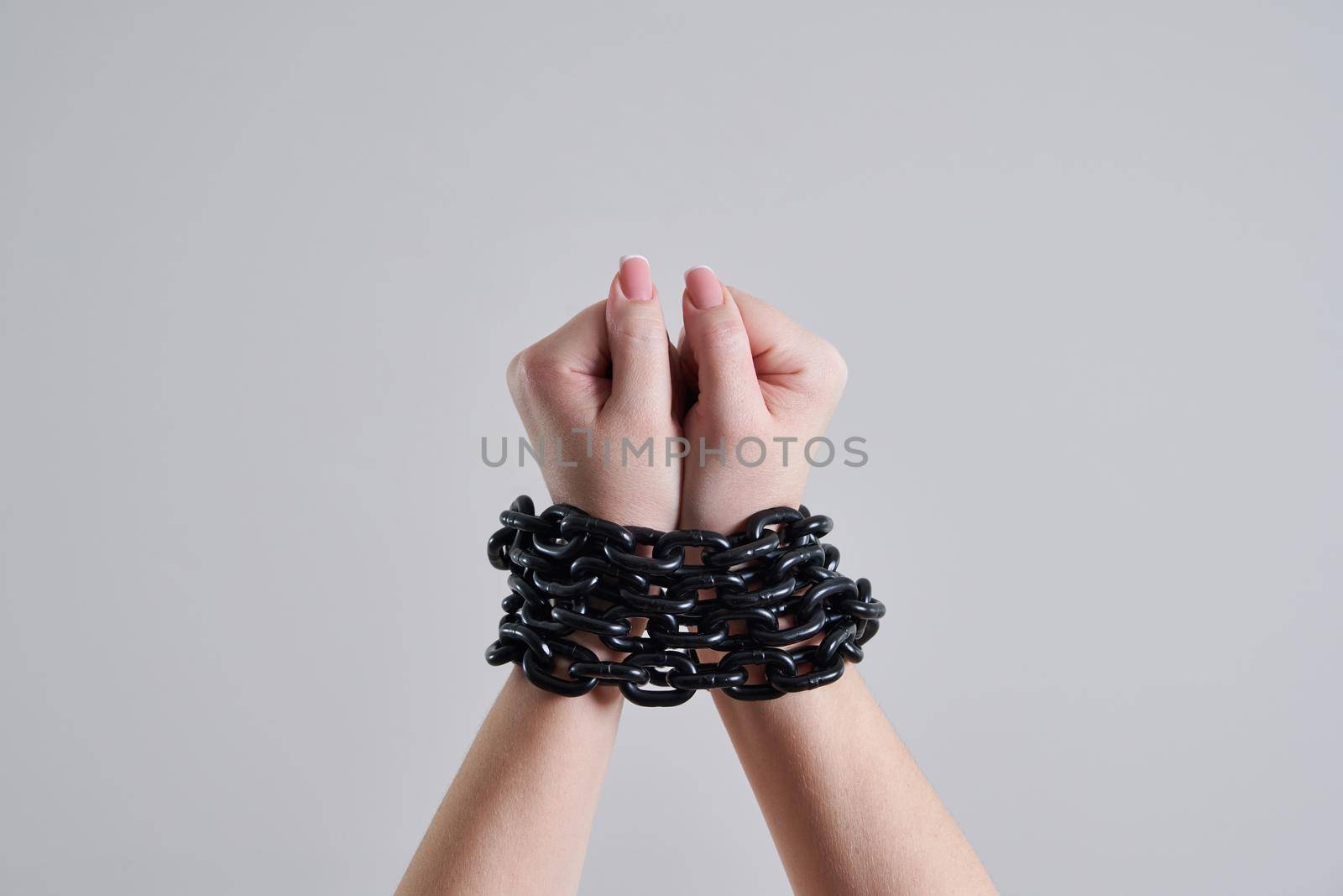 Chained female hands over grey background with copy space