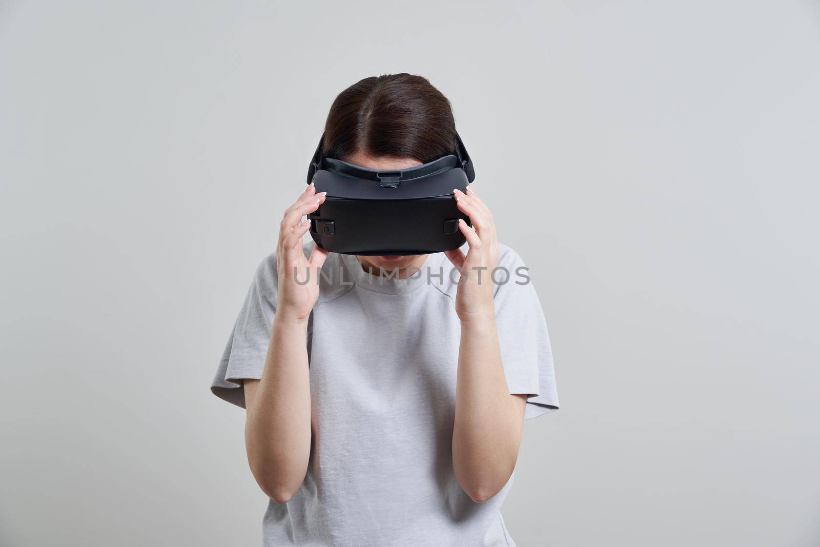 Happy young woman playing on VR glasses indoor. Virtual reality concept with young girl having fun with headset goggles.