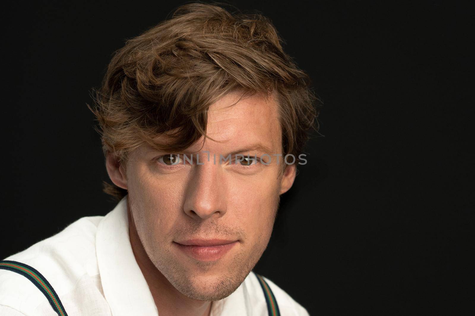 Close up. Handsome young hipster man looking at camera isolated on black background. Copy space on the right.