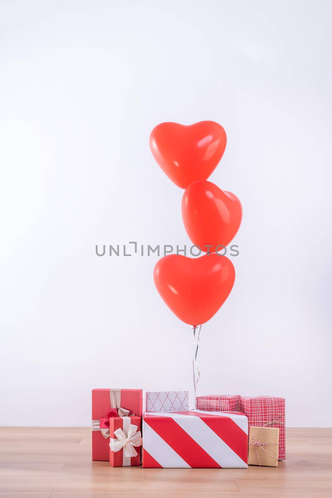 Valentine's day, Mother's day, birthday design concept - Heart helium balloon with gift box on a light wood floor, white wall background, close up. by ROMIXIMAGE