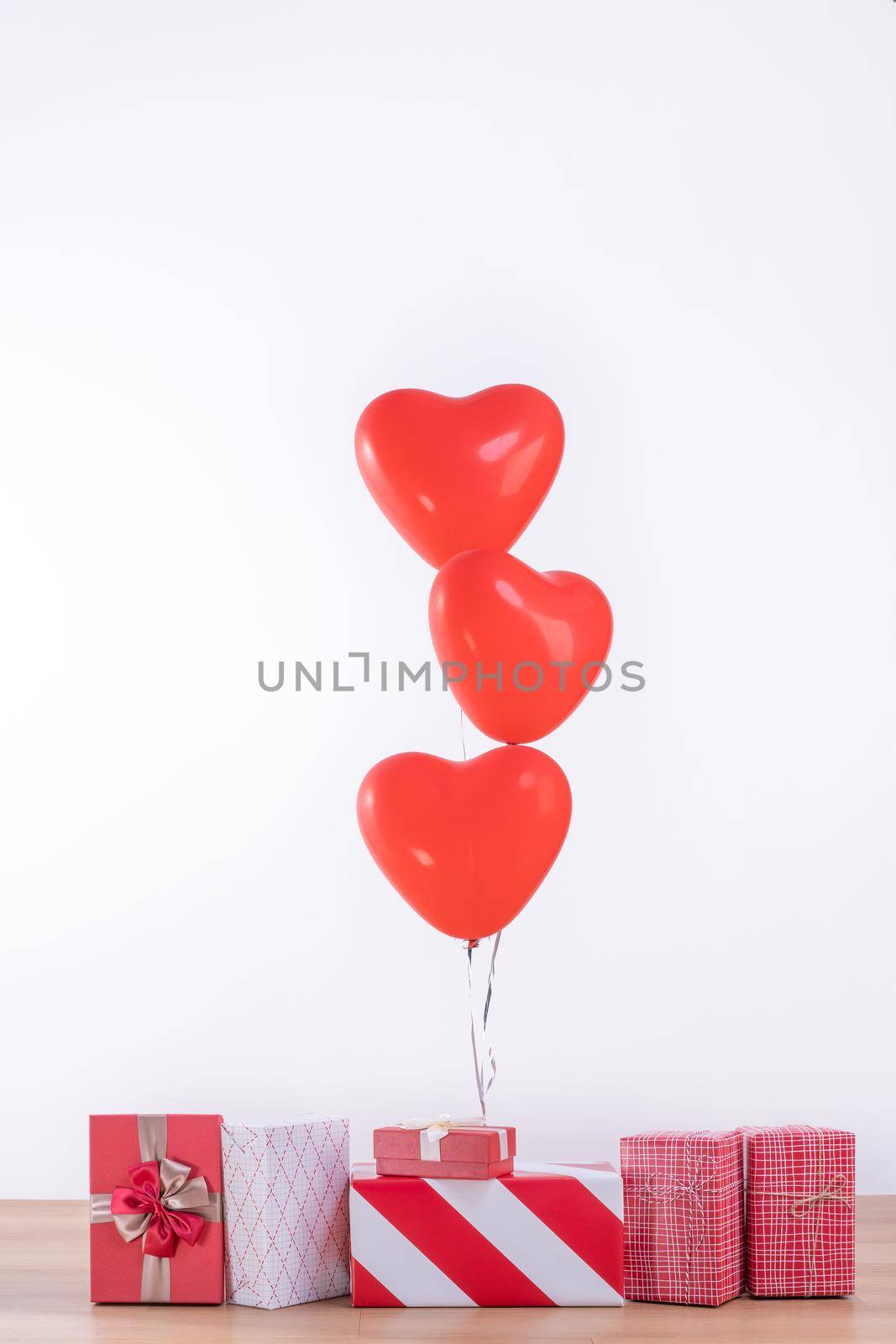 Valentine's day, Mother's day, birthday design concept - Heart helium balloon with gift box on a light wood floor, white wall background, close up. by ROMIXIMAGE