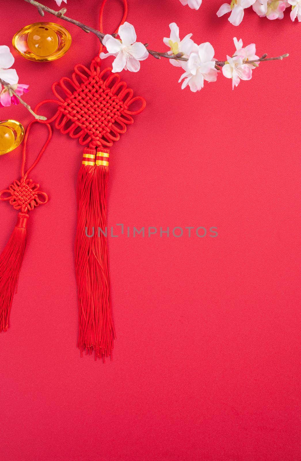 Design concept of Chinese lunar new year - Beautiful Chinese knot with plum blossom isolated on red background, flat lay, top view, overhead layout.