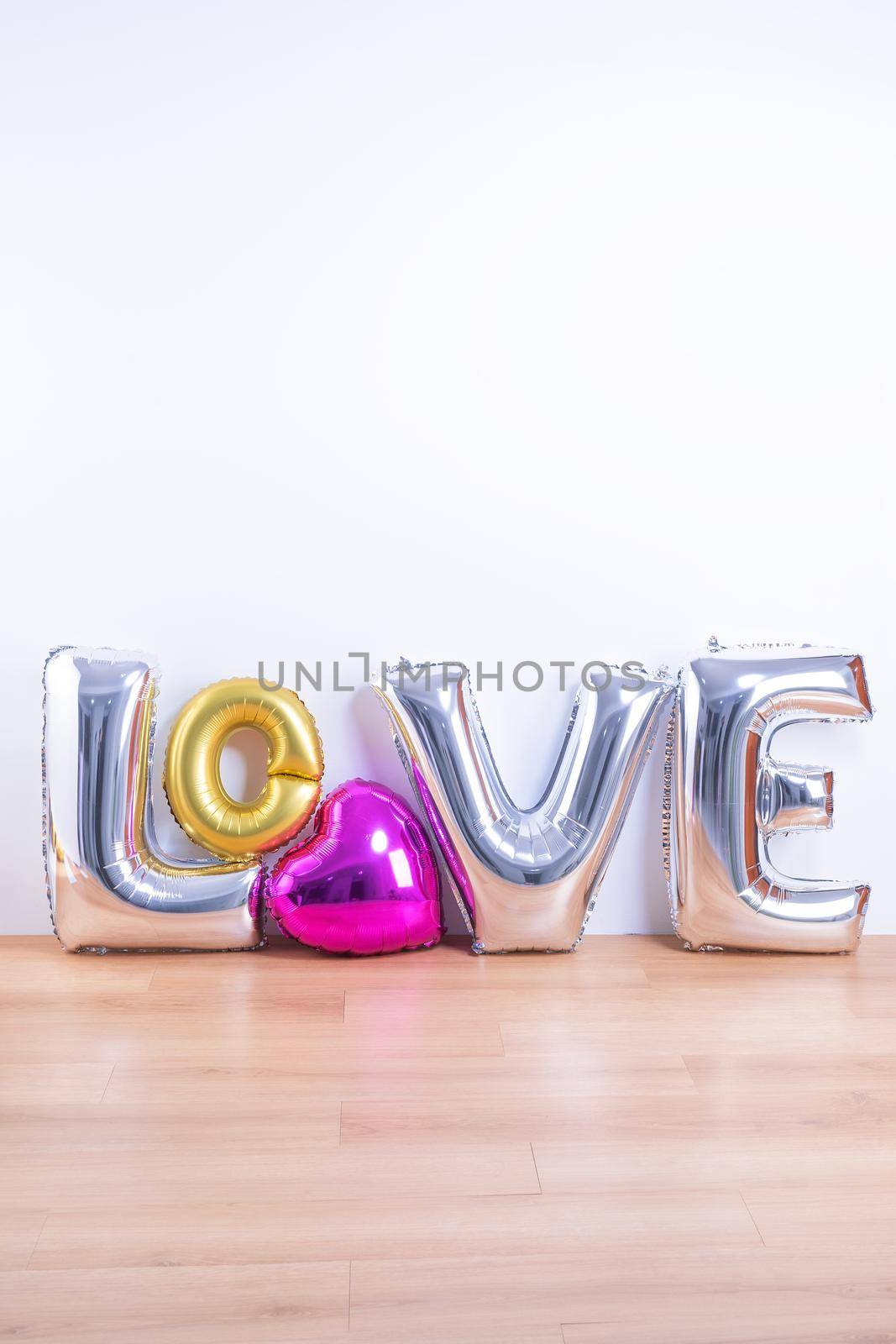 Valentine's day, Mother's day design concept - Beautiful balloon with word love shape on a light wooden floor and white wall background, close up. by ROMIXIMAGE