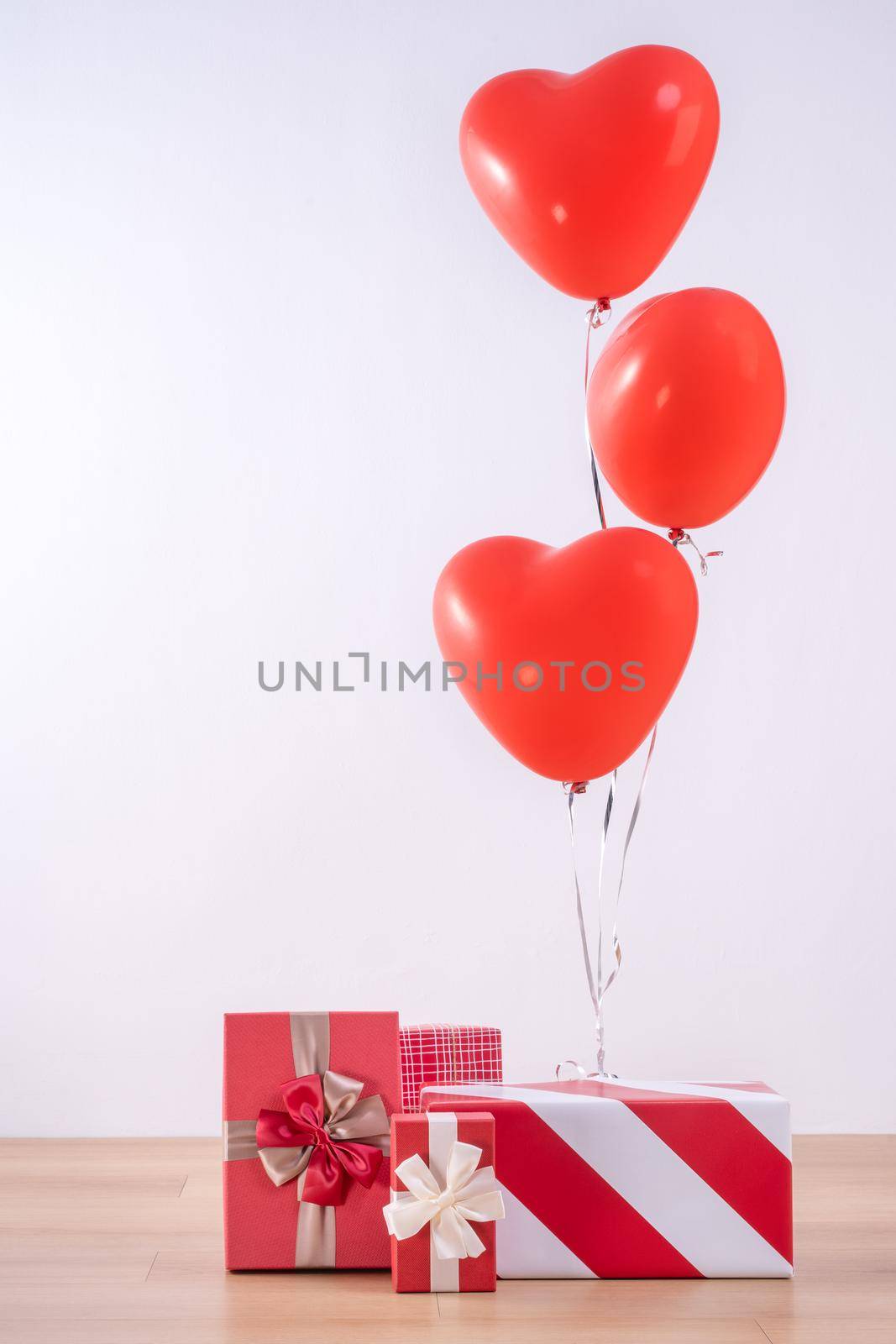 Valentine's day, Mother's day, birthday design concept - Heart helium balloon with gift box on a light wood floor, white wall background, close up.