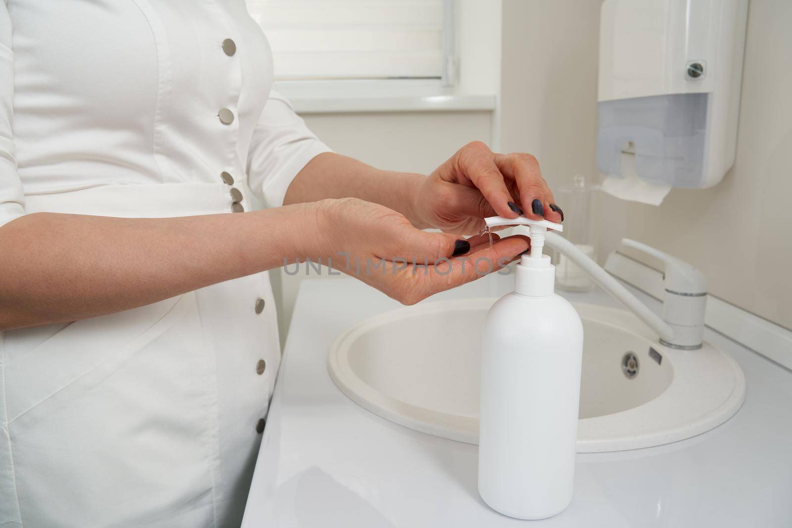 Cropped view of female hands pressing on soap bottle before washing hands