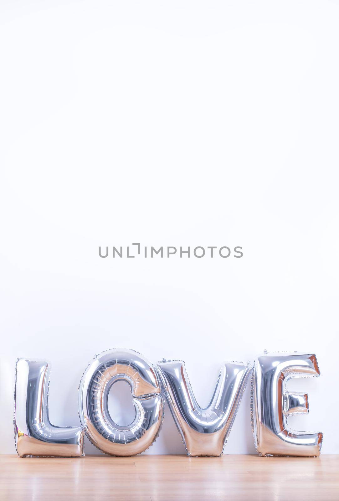 Valentine's day, Mother's day design concept - Beautiful balloon with word love shape on a light wooden floor and white wall background, close up. by ROMIXIMAGE