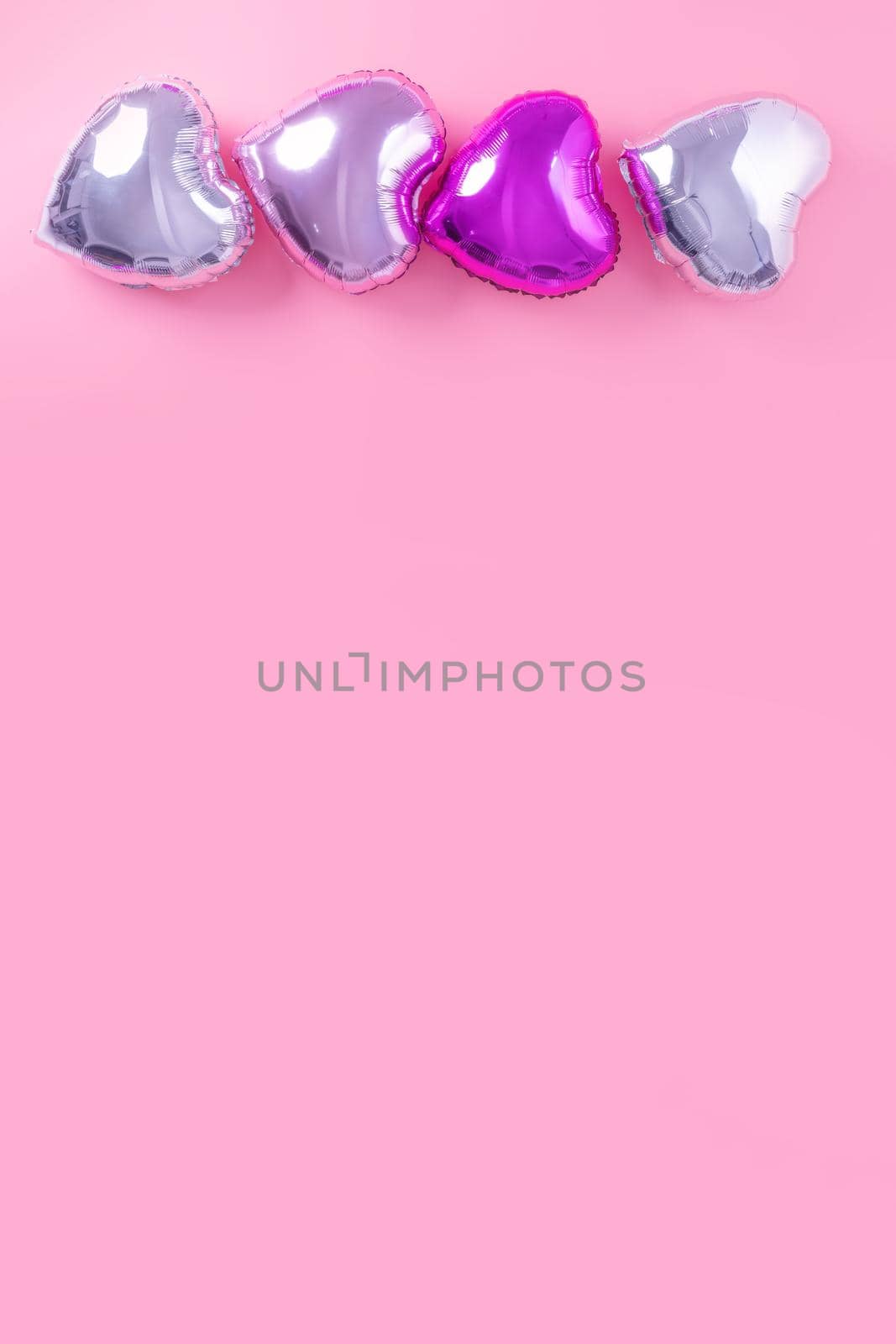 Valentine's Day romantic design concept - Beautiful real heart shape foil balloon isolated on pale pink background, top view, flat lay, overhead above photography.