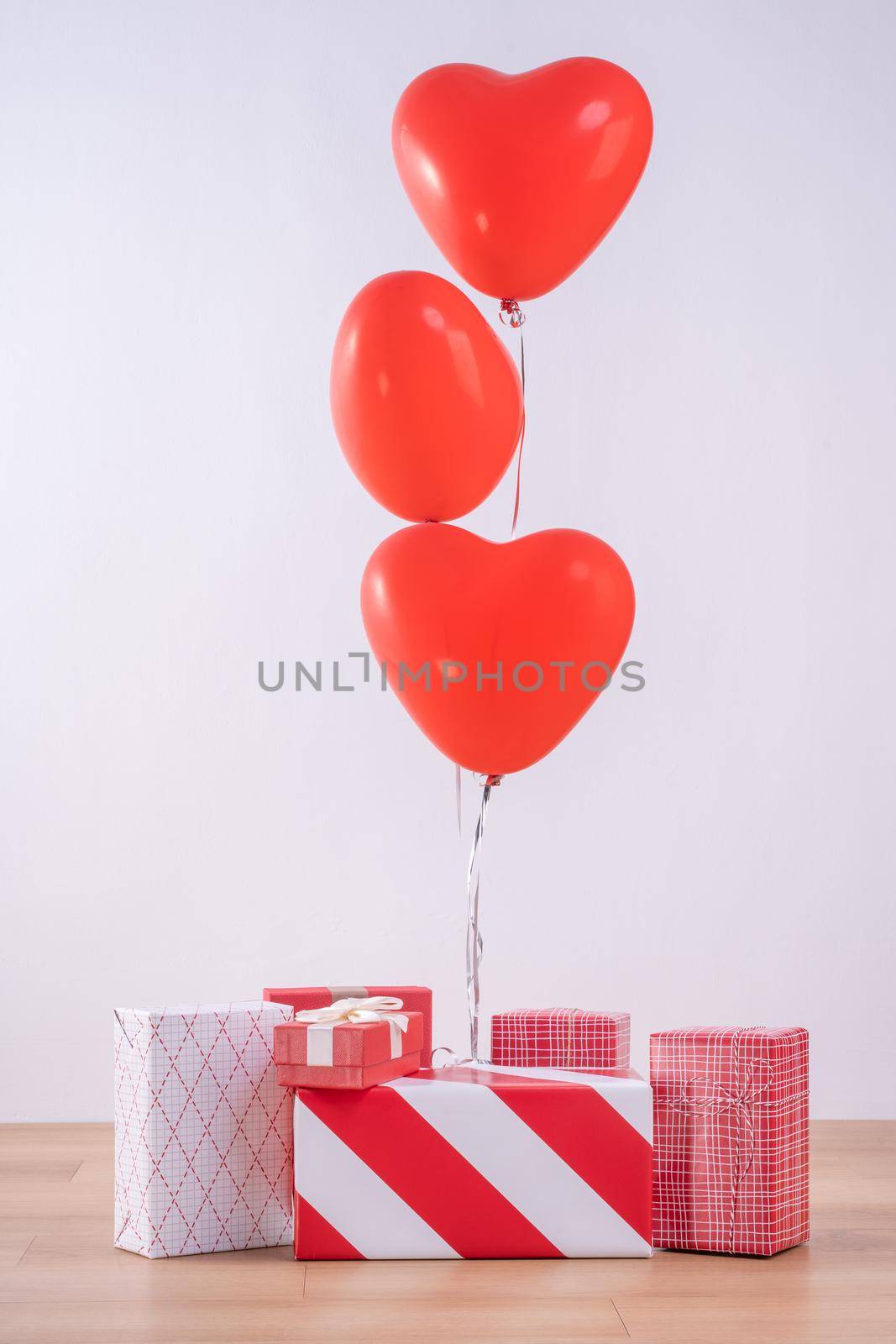 Valentine's day, Mother's day, birthday design concept - Heart helium balloon with gift box on a light wood floor, white wall background, close up.