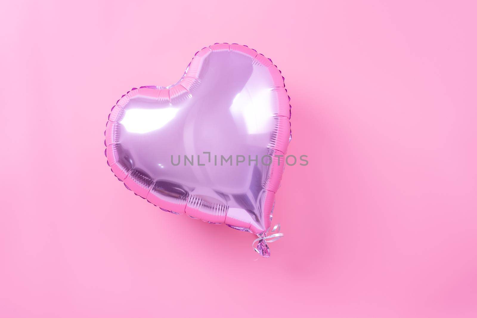 Valentine's Day minimal design concept - Beautiful real heart shape foil balloon isolated on pale pink background, top view, flat lay, overhead above photography.
