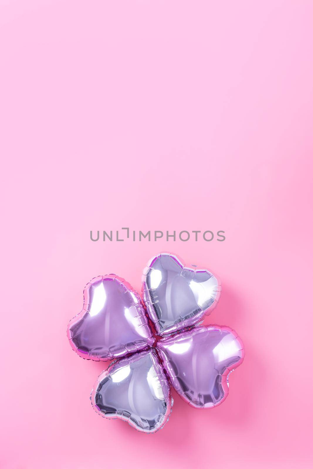 Valentine's Day romantic design concept - Beautiful real heart shape foil balloon isolated on pale pink background, top view, flat lay, overhead above photography.