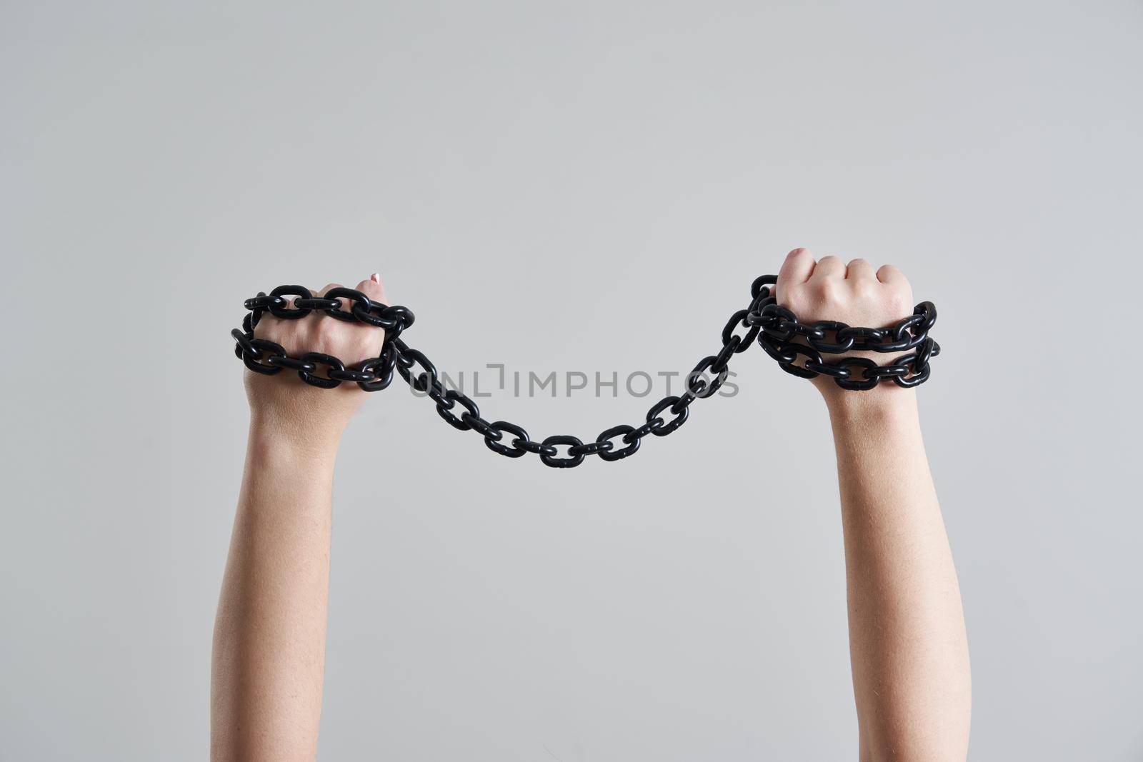 Female hands holding metal metal chain over her head