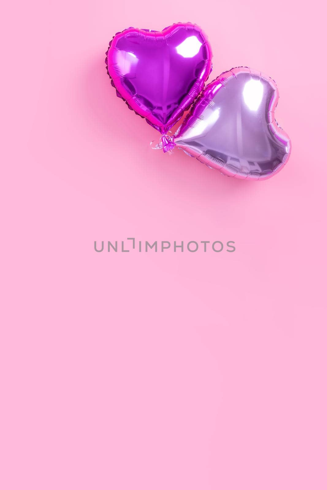 Valentine's Day romantic design concept - Beautiful real heart shape foil balloon isolated on pale pink background, top view, flat lay, overhead above photography.