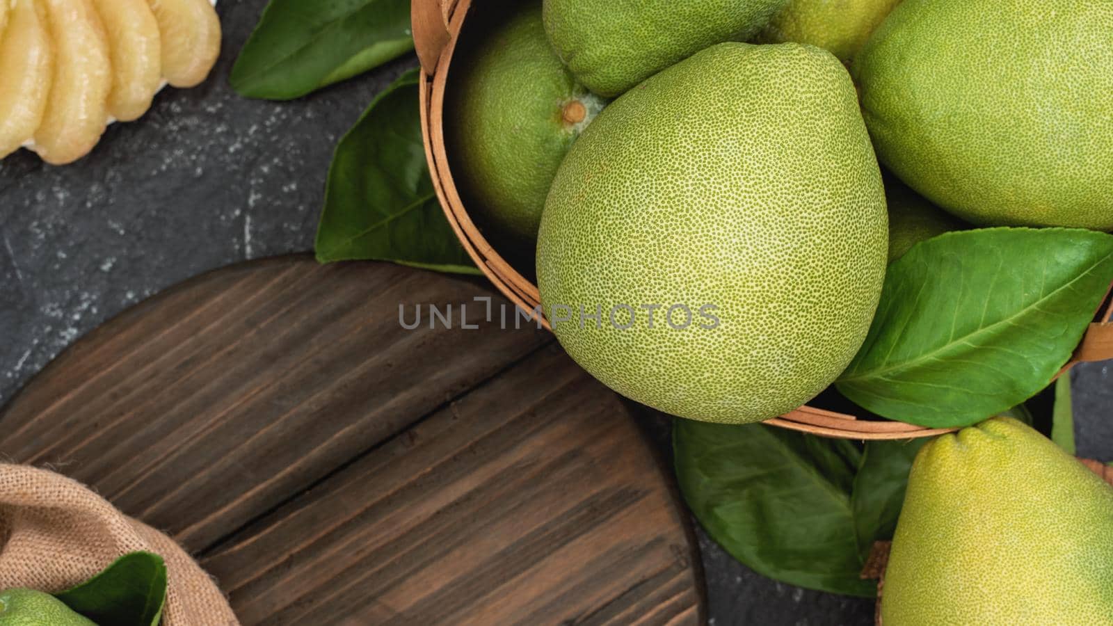 Fresh peeled pomelo, pummelo, grapefruit, shaddock on dark background in bamboo basket. Autumn seasonal fruit, top view, flat lay, tabletop shot.