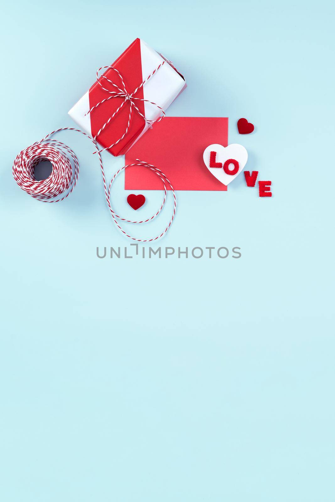 Valentine's Day, Mother's day art design concept for promotion - Red, white wrapped gift box isolated on pastel light blue color background, flat lay, top view.