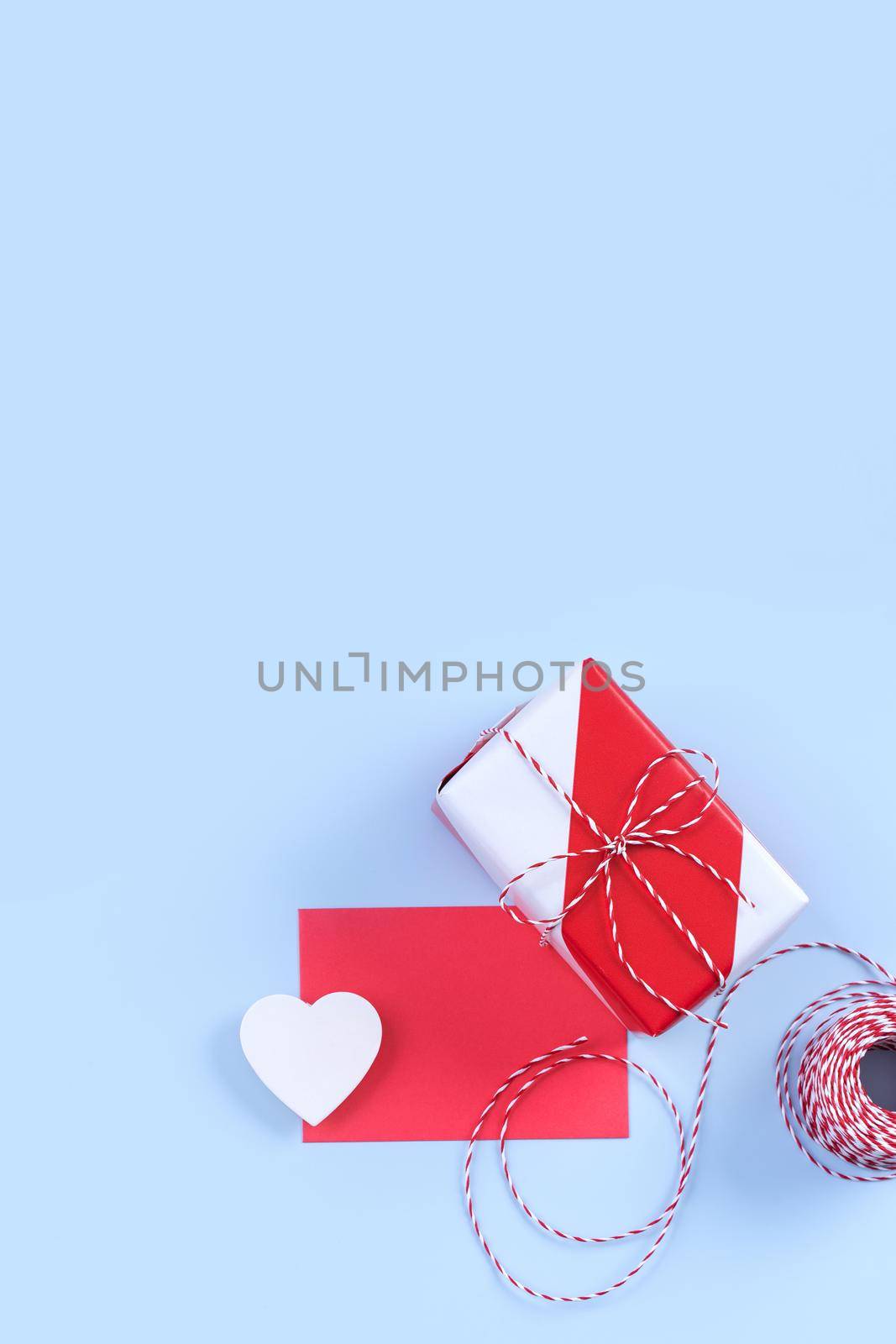 Valentine's Day, Mother's day art design concept for promotion - Red, white wrapped gift box isolated on pastel light blue color background, flat lay, top view.