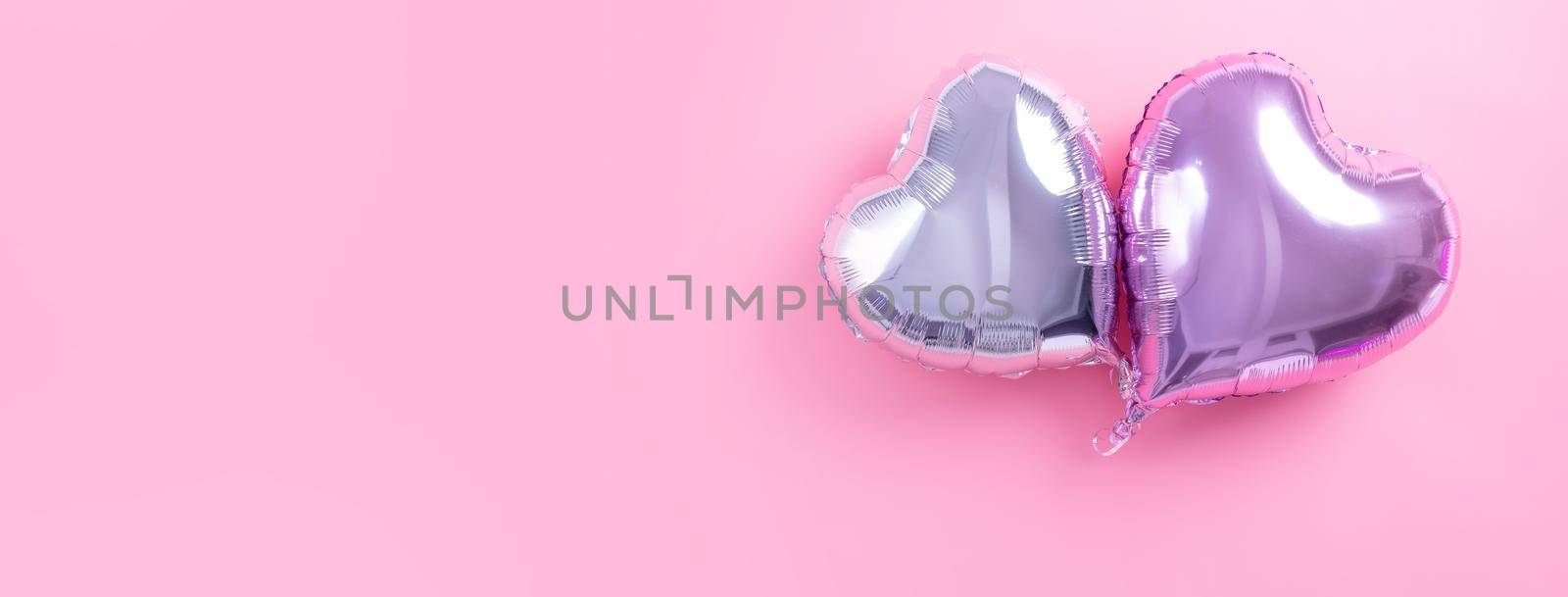 Valentine's Day romantic design concept - Beautiful real heart shape foil balloon isolated on pale pink background, top view, flat lay, overhead above photography.