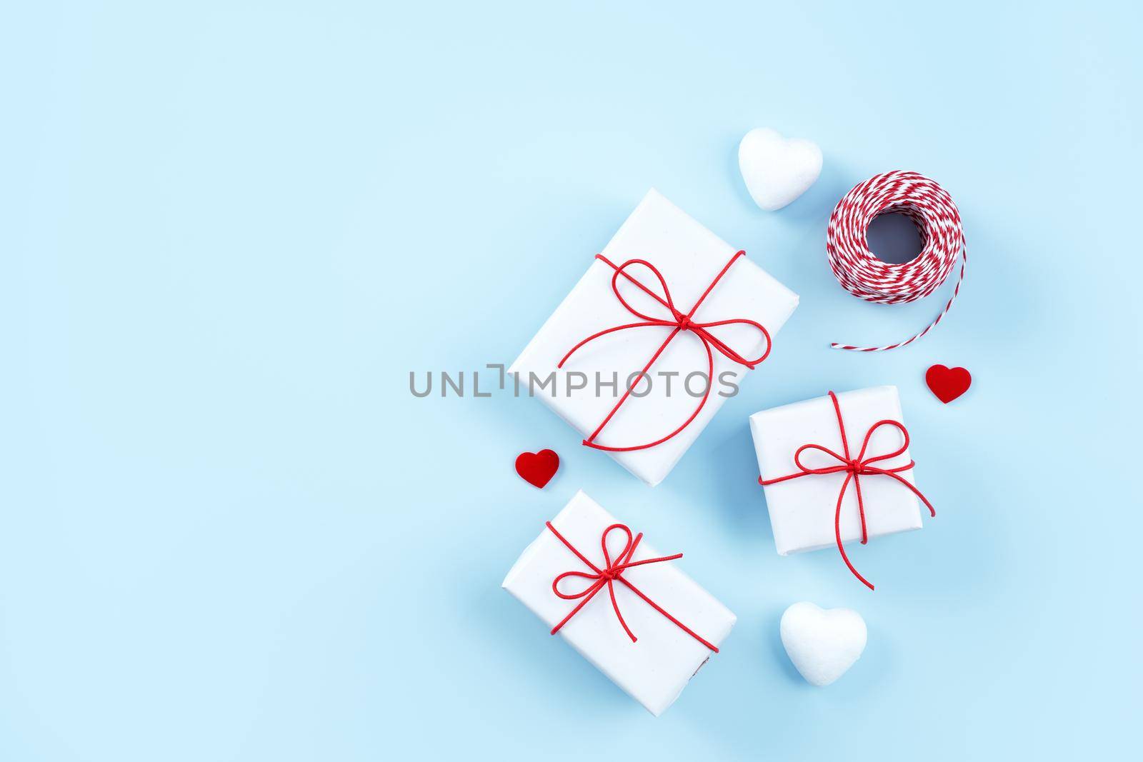 Valentine's Day, Mother's day art design concept - Red, white wrapped gift box isolated on pastel light blue color background, flat lay, top view.