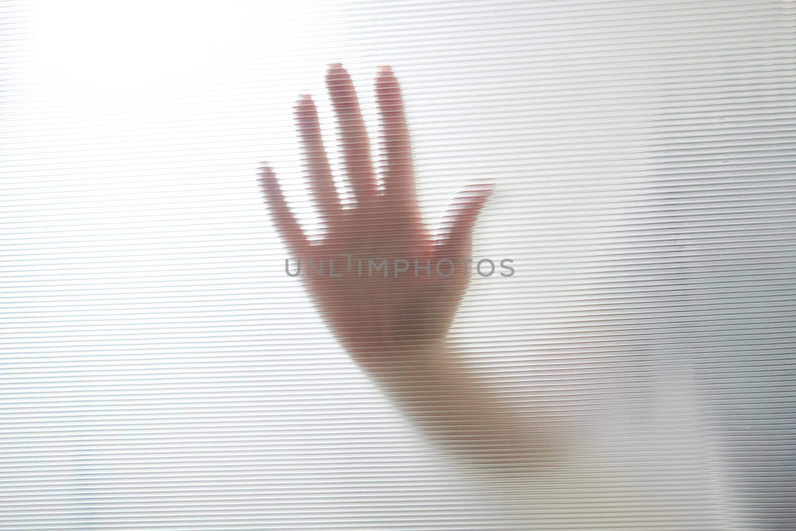 Diffused silhouette of female hands through frosted glass