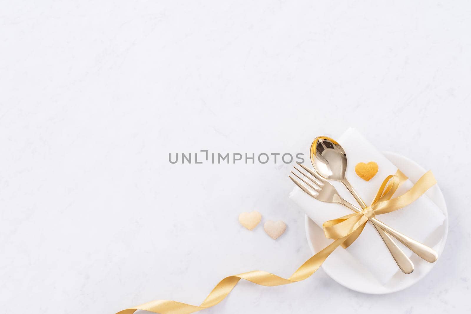 Valentine's Day, Mother's Day, holiday dating meal, banquet design concept - White plate and golden ribbon on marble background, top view, flat lay.