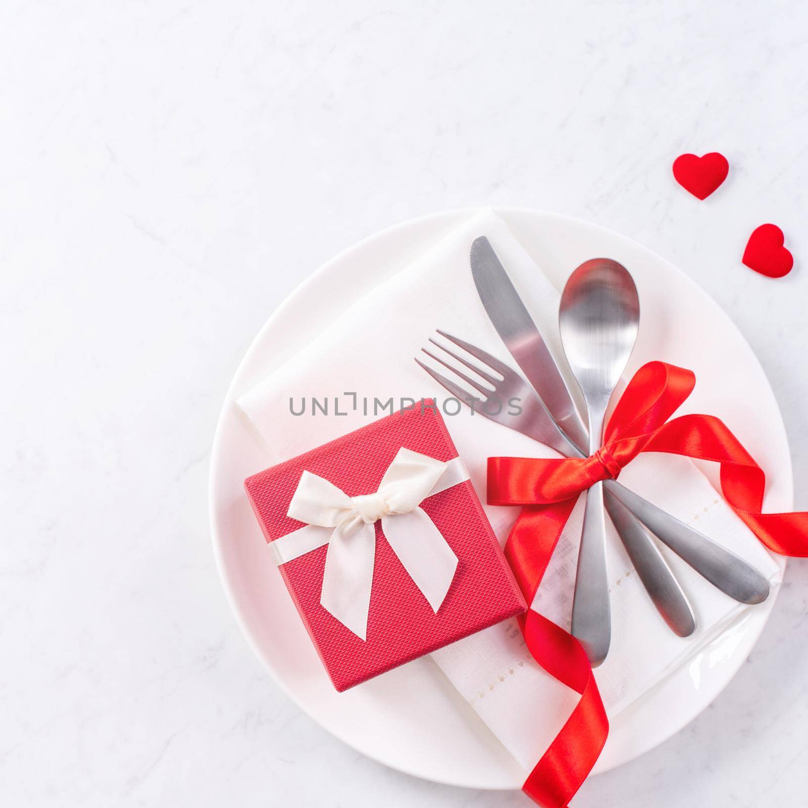 Valentine's Day, Mother's Day, holiday dating meal, banquet design concept - White plate and red ribbon on marble background, top view, flat lay.