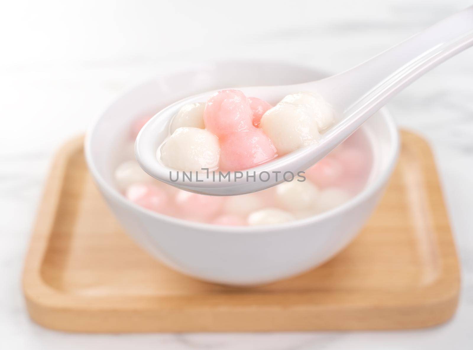 Delicious tang yuan, red and white rice dumpling balls in a small bowl. Asian traditional festive food for Chinese Winter Solstice Festival, close up.