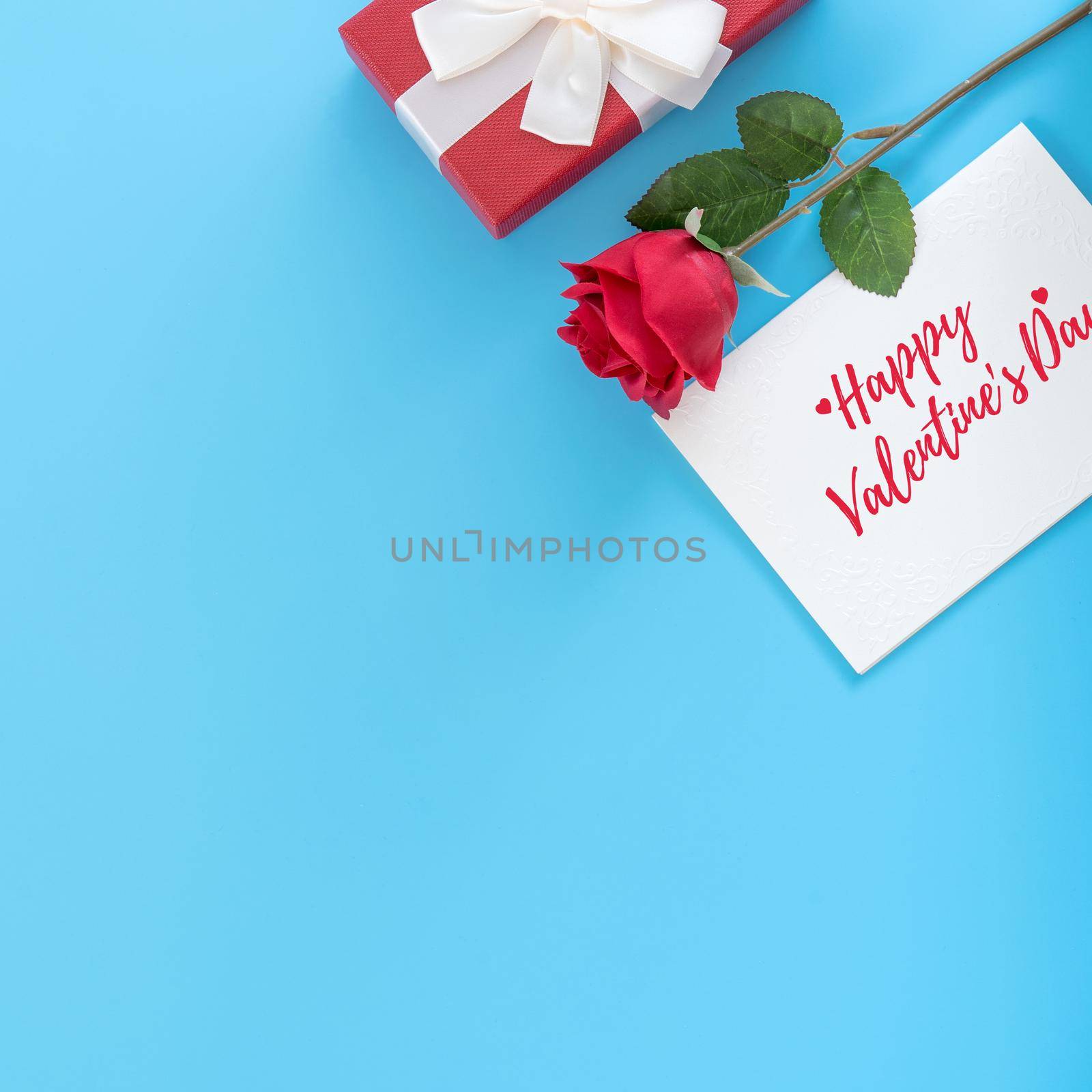 Valentine's Day gift card with greeting word design concept, woman sending gift on vibrant blue background, top view, overhead.