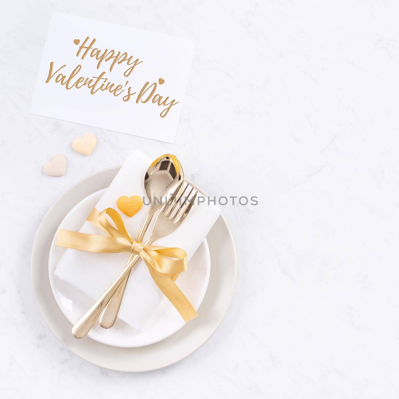 Valentine's Day holiday dating meal, banquet greeting card design concept - White plate and golden color tableware on marble background, top view, flat lay.