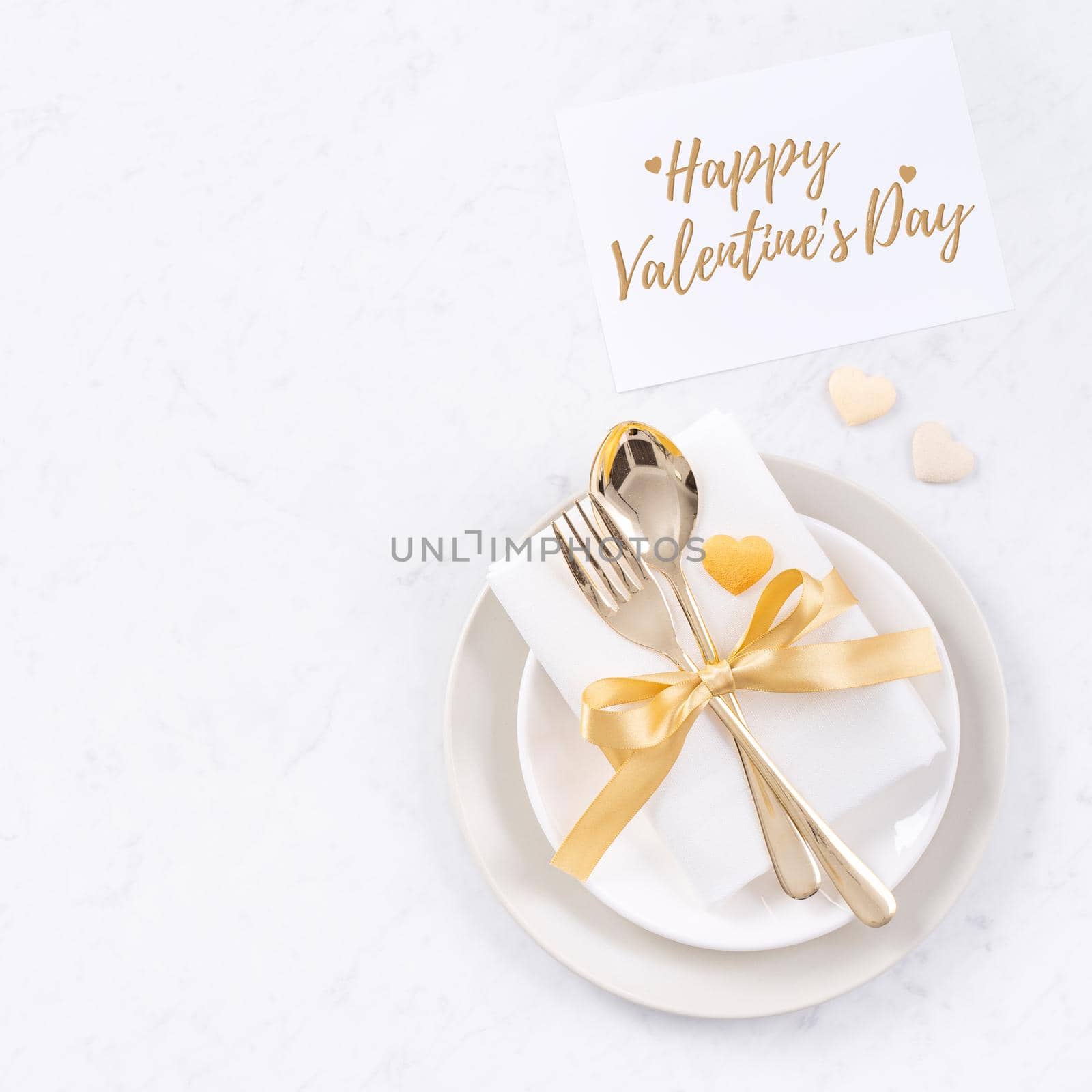 Valentine's Day holiday dating meal, banquet greeting card design concept - White plate and golden color tableware on marble background, top view, flat lay. by ROMIXIMAGE