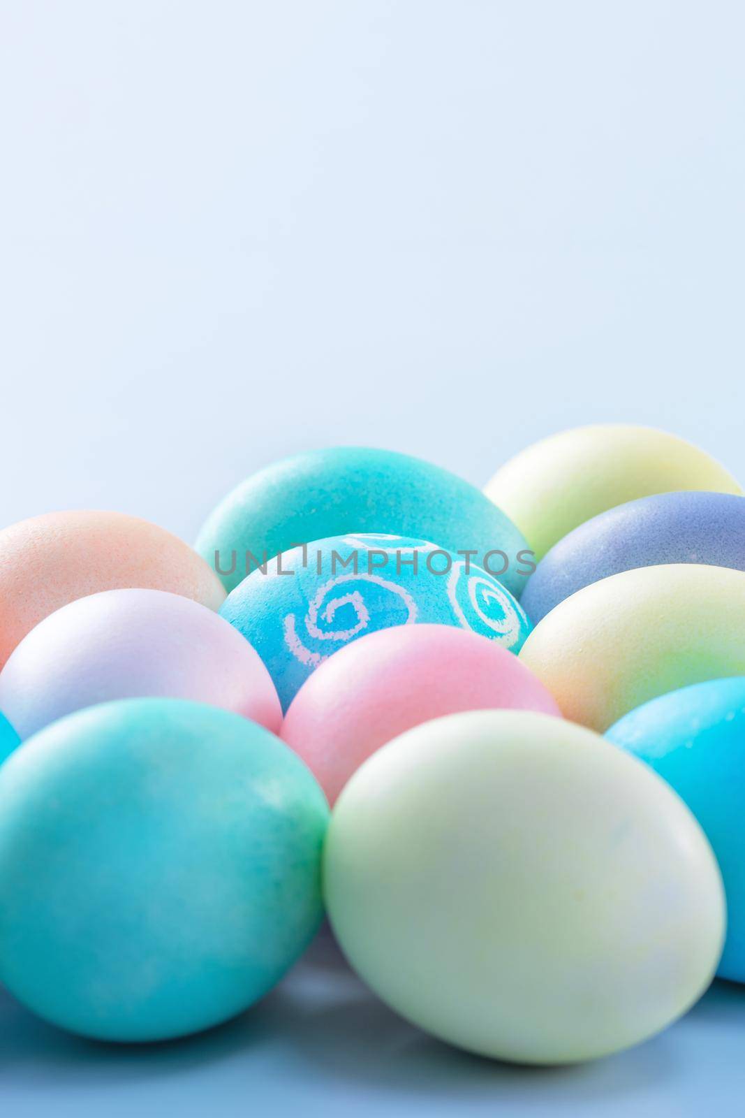 Colorful Easter eggs dyed by colored water isolated on a pale blue background, design concept of Easter holiday activity, close up, copy space.