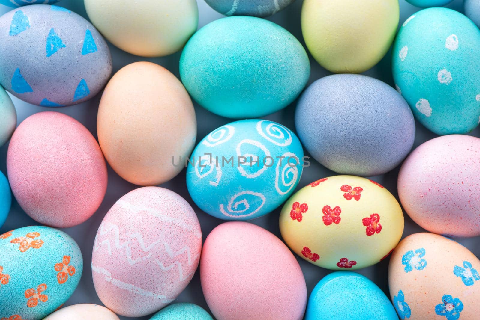Colorful Easter eggs dyed by colored water with beautiful pattern on a pale blue background, design concept of holiday activity, top view, full frame. by ROMIXIMAGE