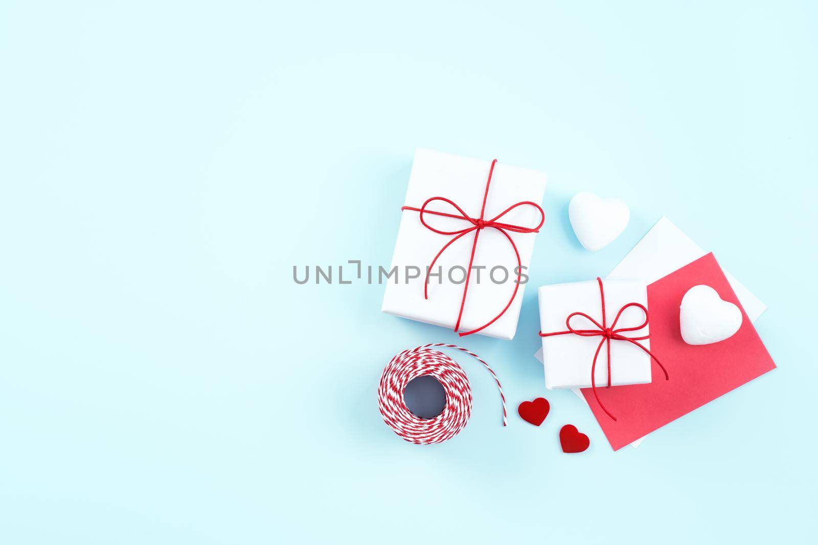 Valentine's Day, Mother's day art design concept - Red, white wrapped gift box isolated on pastel light blue color background, flat lay, top view.