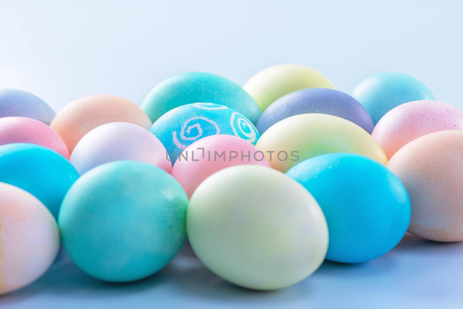 Colorful Easter eggs dyed by colored water isolated on a pale blue background, design concept of Easter holiday activity, close up, copy space.
