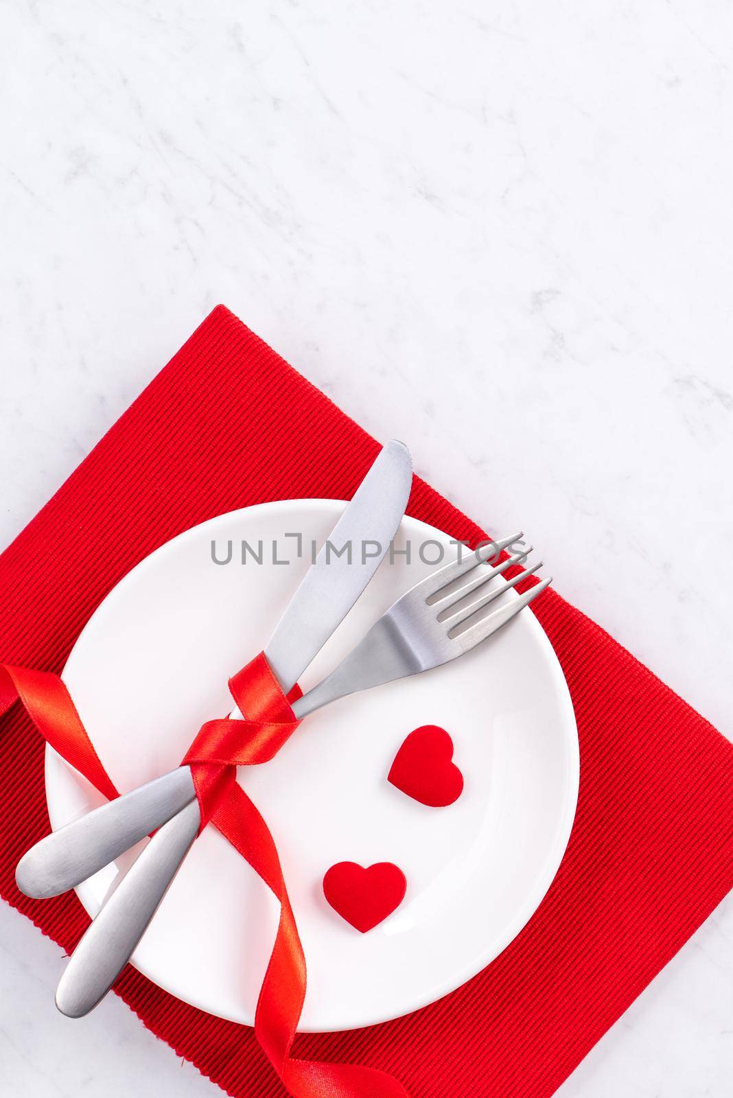 Valentine's Day, Mother's Day, holiday dating meal, banquet design concept - White plate and red ribbon on marble background, top view, flat lay.