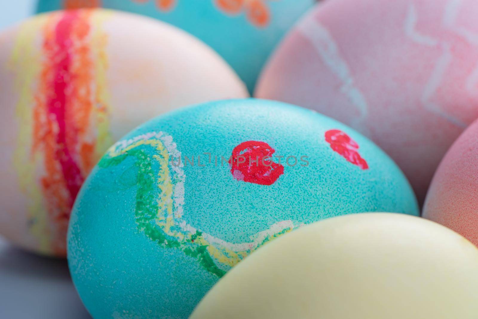 Colorful Easter eggs dyed by colored water isolated on a pale blue background, design concept of Easter holiday activity, close up, copy space.