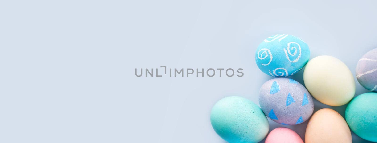 Colorful Easter eggs dyed by colored water with beautiful pattern on a pale blue background, design concept of holiday activity, top view, full frame.