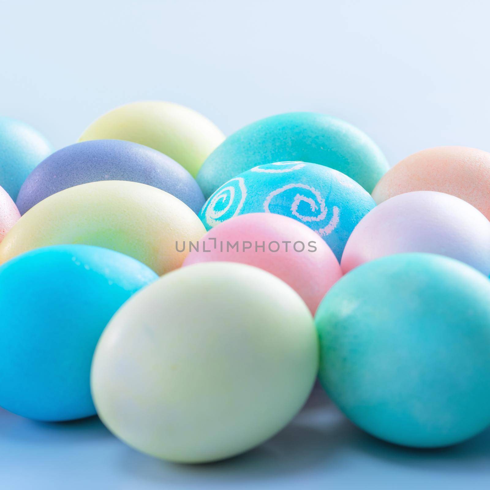 Colorful Easter eggs dyed by colored water isolated on a pale blue background, design concept of Easter holiday activity, close up, copy space.