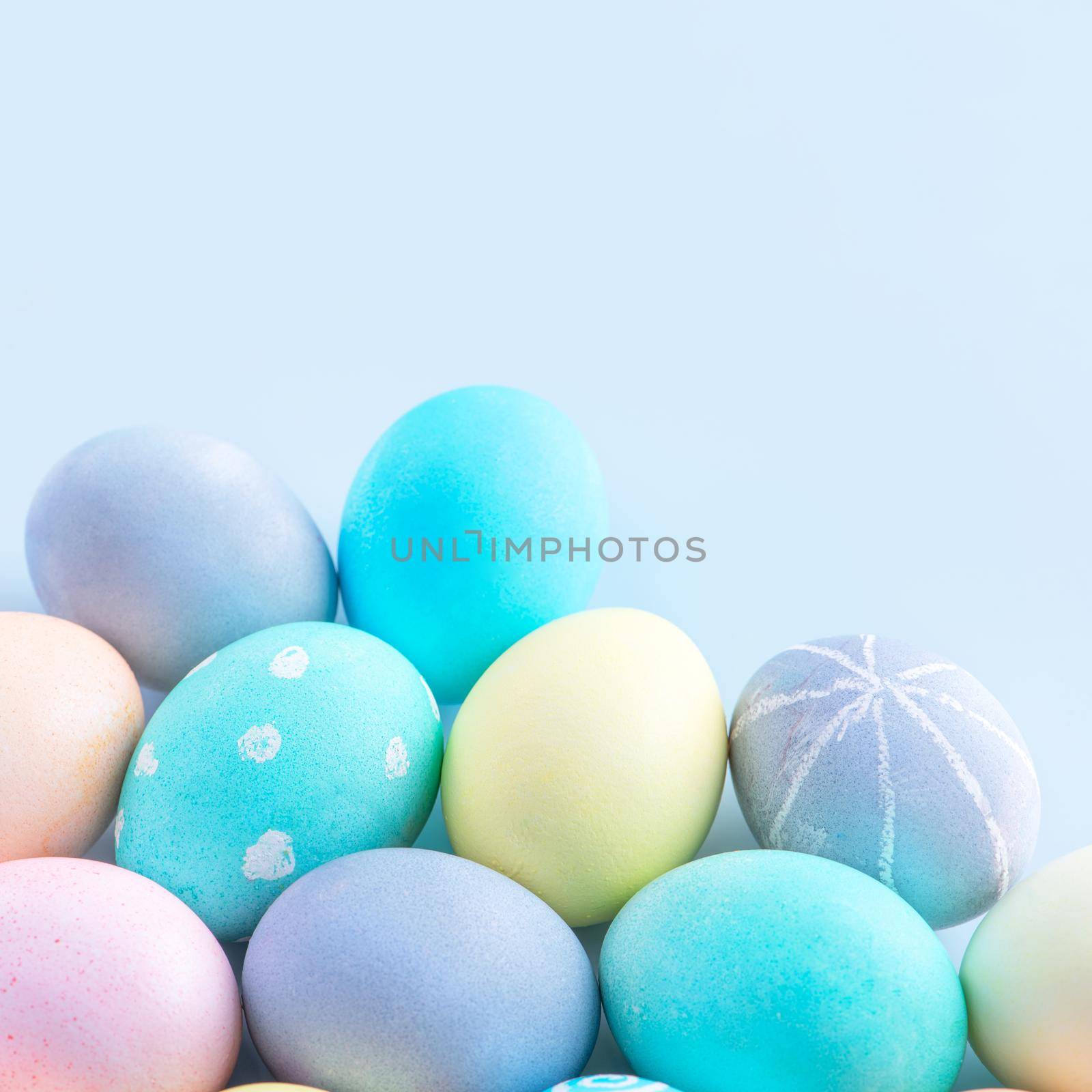 Colorful Easter eggs dyed by colored water isolated on a pale blue background, design concept of Easter holiday activity, close up, copy space.