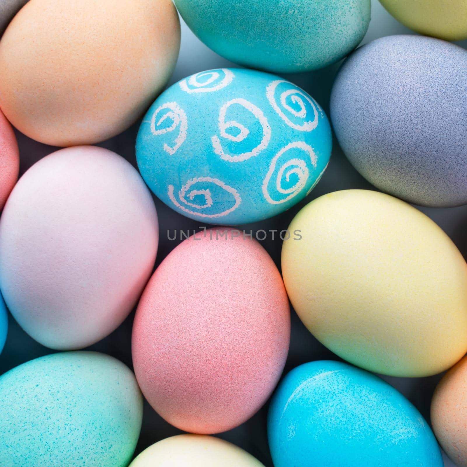 Colorful Easter eggs dyed by colored water with beautiful pattern on a pale blue background, design concept of holiday activity, top view, full frame.