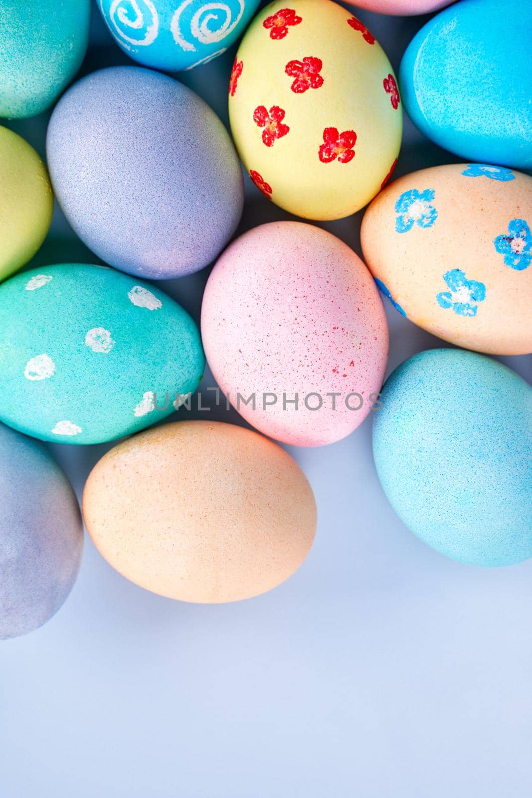 Colorful Easter eggs dyed by colored water with beautiful pattern on a pale blue background, design concept of holiday activity, top view, copy space.