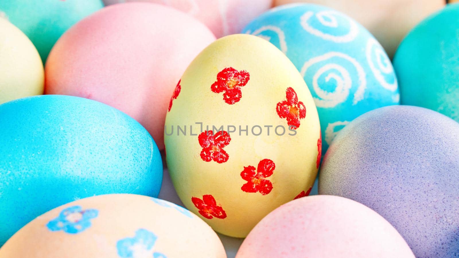 Colorful Easter eggs dyed by colored water with beautiful pattern on a pale blue background, design concept of holiday activity, top view, full frame.
