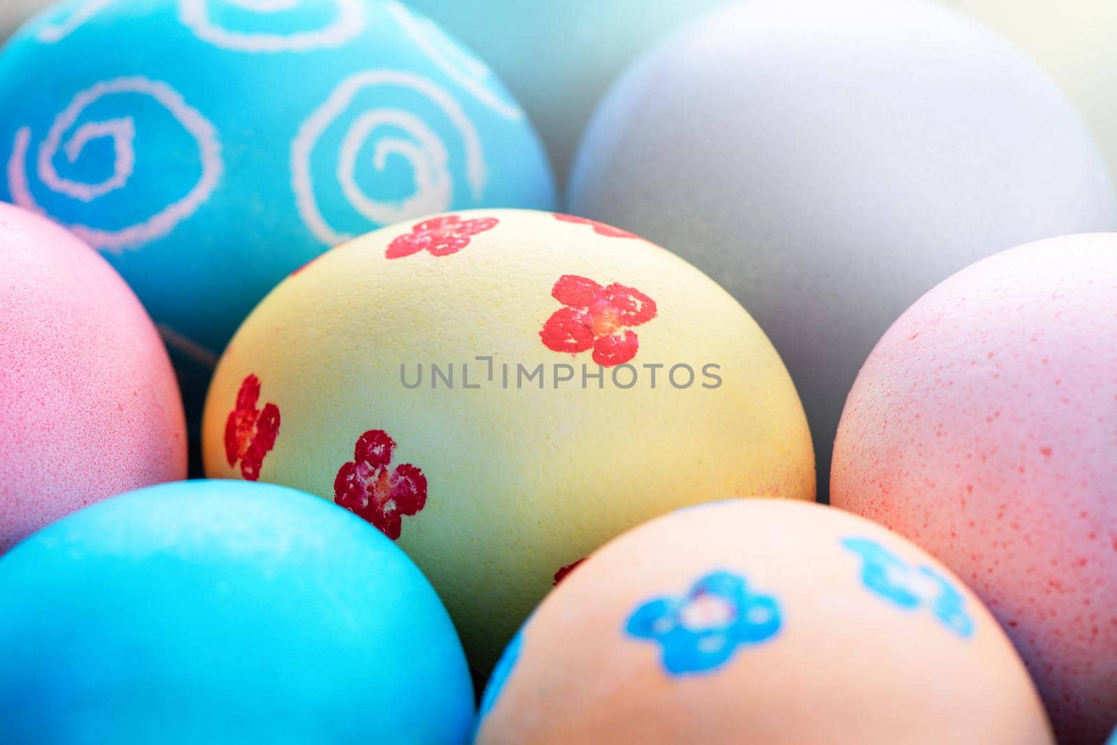 Colorful Easter eggs dyed by colored water with beautiful pattern on a pale blue background, design concept of holiday activity, top view, full frame.